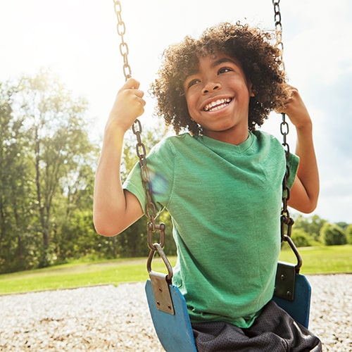 A boy swinging while laughing