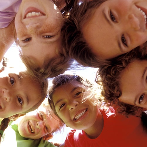 A group of children playing in the sun while embracing each other