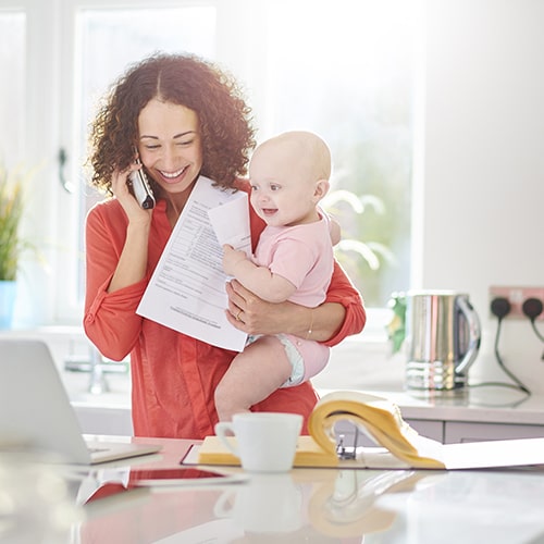 A mother making an emergency call to the dentist while holding her baby
