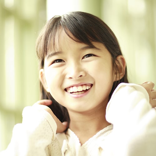 A girl smiling while touching her hair