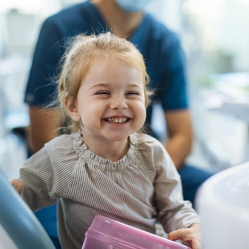 A little girl sitting in the dentist's chair while laughing