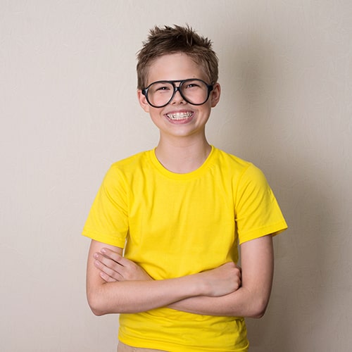 A boy with space maintainers smiling while crossing his arms