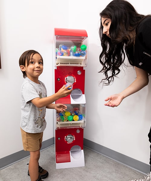 A child and one of our Go Kids Dental assistants in a toy machine