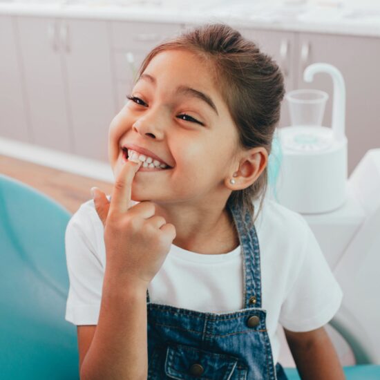 girl pointing to her teeth at the dentist